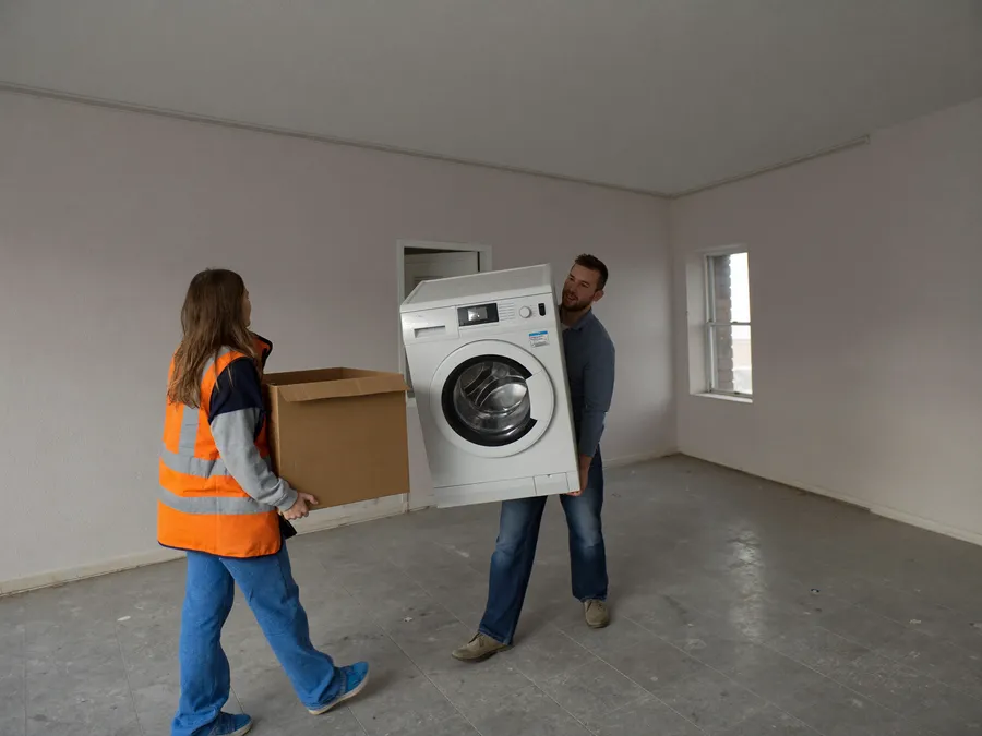 Entrümpelung: Altgerät wird aus der leeren Wohnung getragen